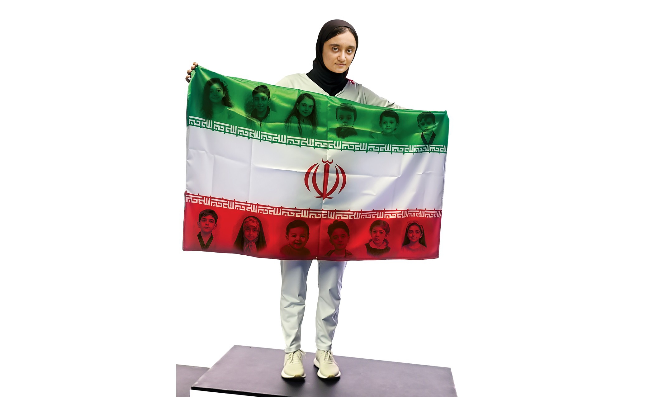 قهرمان ایرانی با پرچم منقش به تصویر کودکان شهید جنگ ۱۲روزه روی سکوی آسیایی